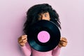 African american woman with afro hair holding vinyl disc afraid and shocked with surprise and amazed expression, fear and excited