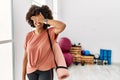 African american woman with afro hair holding yoga mat at pilates room smiling and laughing with hand on face covering eyes for Royalty Free Stock Photo