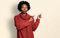 African american woman with afro hair pointing with fingers to the side smiling looking to the side and staring away thinking Royalty Free Stock Photo