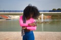 African-American woman with afro hair and sportswear, wearing fluorescent pink t-shirt and leggings, opening a running app on her