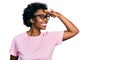 African american woman with afro hair wearing casual clothes and glasses very happy and smiling looking far away with hand over Royalty Free Stock Photo