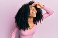 African american woman with afro hair wearing casual pink shirt very happy and smiling looking far away with hand over head Royalty Free Stock Photo