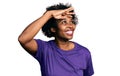 African american woman with afro hair wearing casual purple t shirt very happy and smiling looking far away with hand over head Royalty Free Stock Photo