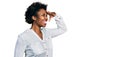 African american woman with afro hair wearing casual white t shirt very happy and smiling looking far away with hand over head Royalty Free Stock Photo