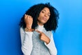 African american woman with afro hair wearing casual winter sweater in hurry pointing to watch time, impatience, looking at the Royalty Free Stock Photo