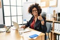 African american woman with afro hair working at the office wearing operator headset doing happy thumbs up gesture with hand Royalty Free Stock Photo