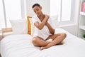 African american woman applying skin treatment sitting on bed at bedroom Royalty Free Stock Photo