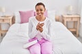 African american woman applying skin treatment sitting on bed at bedroom Royalty Free Stock Photo