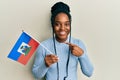 African american woman with braided hair holding haiti flag smiling happy pointing with hand and finger