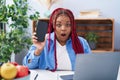 African american woman with braided hair holding smartphone showing blank screen scared and amazed with open mouth for surprise, Royalty Free Stock Photo