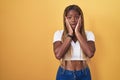 African american woman with braided hair standing over yellow background afraid and shocked, surprise and amazed expression with Royalty Free Stock Photo