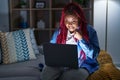 African american woman with braided hair using computer laptop at night angry and mad raising fist frustrated and furious while Royalty Free Stock Photo