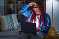 African american woman with braided hair using computer laptop at night very happy and smiling looking far away with hand over Royalty Free Stock Photo