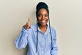 African american woman with braided hair wearing casual blue shirt smiling with an idea or question pointing finger up with happy Royalty Free Stock Photo