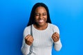 African american woman with braided hair wearing casual white sweater very happy and excited doing winner gesture with arms