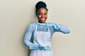 African american woman with braided hair wearing cleaner apron and gloves gesturing with hands showing big and large size sign, Royalty Free Stock Photo