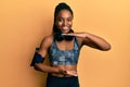 African american woman with braided hair wearing sportswear and arm band gesturing with hands showing big and large size sign, Royalty Free Stock Photo