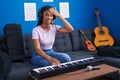 African american woman with braids playing piano keyboard at music studio stressed and frustrated with hand on head, surprised and