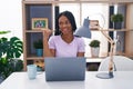 African american woman with braids using laptop at home smiling with happy face looking and pointing to the side with thumb up Royalty Free Stock Photo