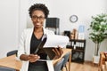 African american woman business worker smiling confident holding clipboard at office Royalty Free Stock Photo