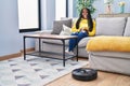 African american woman cleaning floor using vacuum clean robot at home Royalty Free Stock Photo