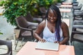 African american woman closing laptop sitting on table at coffee shop terrace