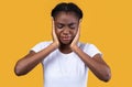 African American Woman Covering Ears Suffering From Otitis, Yellow Background