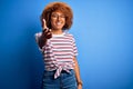 African American woman with curly hair on vacation wearing summer hat and striped t-shirt smiling friendly offering handshake as Royalty Free Stock Photo