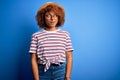 African American woman with curly hair on vacation wearing summer hat and striped t-shirt smiling looking to the side and staring Royalty Free Stock Photo