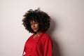 African American woman with curly hair wearing red top over white background. Royalty Free Stock Photo