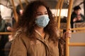 African-American woman with disposable mask on bus