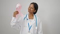 African american woman doctor holding breast cancer awareness pink ribbon over isolated white background Royalty Free Stock Photo