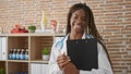 African american woman doctor holding clipboard smiling at the clinic Royalty Free Stock Photo