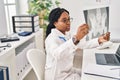 African american woman doctor looking xray sitting on table at clinic Royalty Free Stock Photo