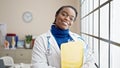 African american woman doctor smiling confident holding document on clipboard at clinic Royalty Free Stock Photo