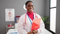 African american woman doctor smiling confident holding medical report at clinic Royalty Free Stock Photo
