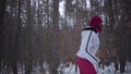 Scared African american young woman dressed warm wearing a red hat, scarf and white jacket running through the snowy