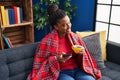 African american woman drinking coffee and using smartphone at home Royalty Free Stock Photo