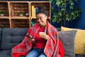 African american woman drinking coffee and using smartphone at home Royalty Free Stock Photo