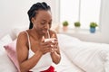 African american woman drinking cup of coffee sitting on bed at bedroom Royalty Free Stock Photo