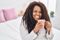 African american woman drinking cup of coffee sitting on bed at bedroom Royalty Free Stock Photo