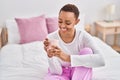 African american woman drinking cup of coffee sitting on bed at bedroom Royalty Free Stock Photo