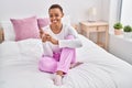 African american woman drinking cup of coffee sitting on bed at bedroom Royalty Free Stock Photo