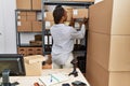 African american woman ecommerce business worker holding package of shelving at office