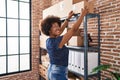 African american woman ecommerce business worker organize packages on shelving at office Royalty Free Stock Photo