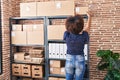 African american woman ecommerce business worker organize packages on shelving at office