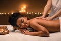 African american woman enjoying romantic atmosphere during body massage Royalty Free Stock Photo