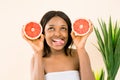 African-American woman with a grapefruit on a white background, showing her tongue. Beauty skin care. Copy space