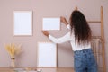 African American woman hanging empty frame on pale rose wall over table in room, back view. Mockup for design Royalty Free Stock Photo