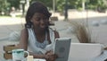 African american woman have video conferance on her tablet sitting in outside cafe